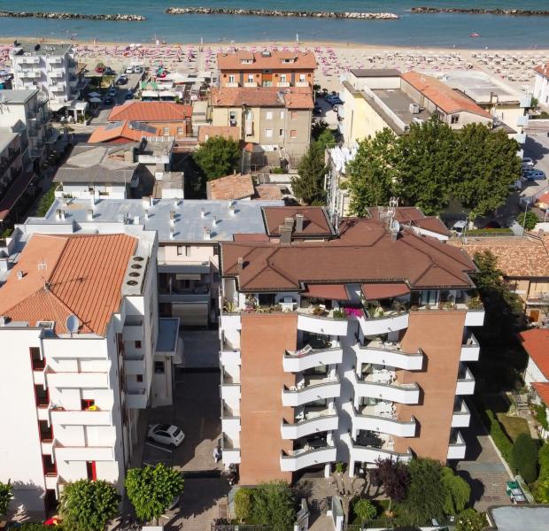 Aerial view of buildings and beach with umbrellas.