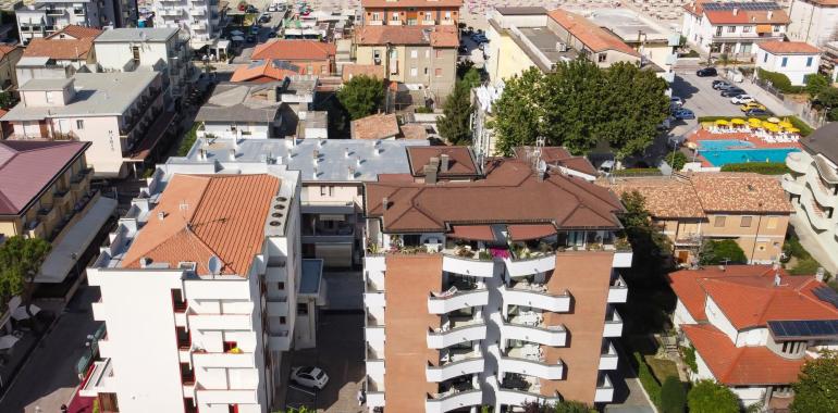 Vista aerea di edifici e spiaggia con ombrelloni.