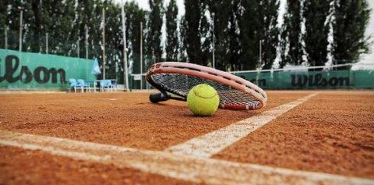 Racchetta e pallina da tennis su campo in terra rossa.